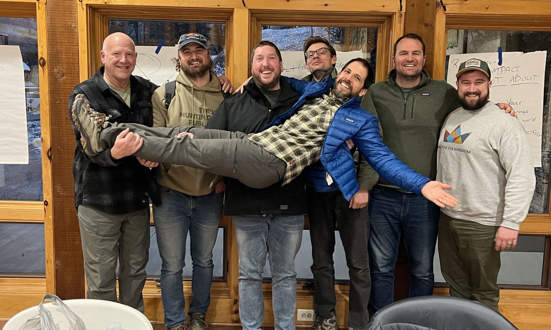 John laughing with a group of men at a Gen1 retreat, holding one of them sideways